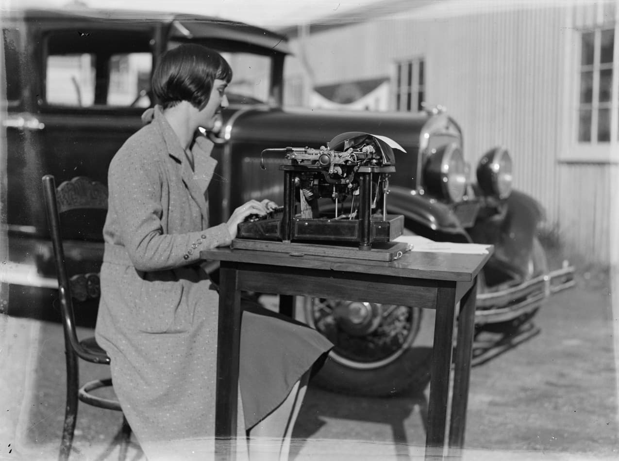 A woman seated at a desk with a typewriter