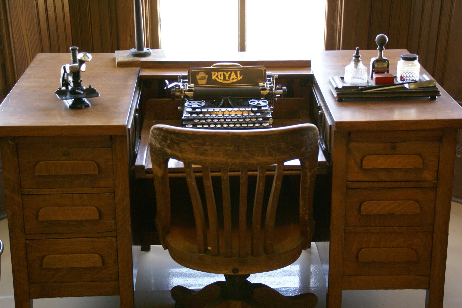 A vintage typewriter on a wooden desk in a railway office